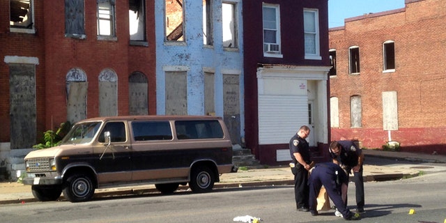 FILE - In this May 24, 2015, file photo, police pick up a pair of shoes after a double shooting in Baltimore. Residents in West Baltimore say theyve been victims of excessive policing in this neighborhood where street crime and drug-dealing have been endemic. Now, one month after riots erupted in the wake of the death of Freddie Gray in police custody, homicides and shootings are up and those same residents feel like theyve been abandoned and left to fend for themselves. (Colin Campbell/The Baltimore Sun via AP, File)