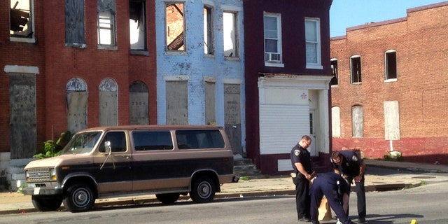FILE - In this May 24, 2015, file photo, police pick up a pair of shoes after a double shooting in Baltimore. Residents in West Baltimore say theyve been victims of excessive policing in this neighborhood where street crime and drug-dealing have been endemic. Now, one month after riots erupted in the wake of the death of Freddie Gray in police custody, homicides and shootings are up and those same residents feel like theyve been abandoned and left to fend for themselves. (Colin Campbell/The Baltimore Sun via AP, File)
