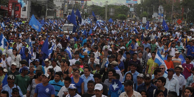 Thousands march in support of President Juan Orlando Hernández in the capital city of Tegucigalpa, Honduras, Sunday, June 28, 2015. President Hernández has been under pressure over a corruption scandal that involved the alleged embezzlement of as much as $120 million from the Central American country's Social Security Institute. Another scandal involves selling overpriced or defective medicines to the government. (AP Photo/Fernando Antonio)