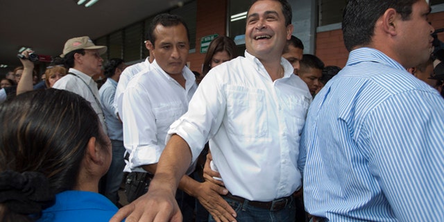 FILE - In this Nov. 24, 2013, file photo, then National Party Presidential Candidate Juan Orlando Hernandez, second from right, greets supporters at a polling station in Tegucigalpa, Honduras. Now as President of Honduras, Hernandez has acknowledged Wednesday, June 3, 2015, that his election campaign received financing from businesspeople linked to a social security embezzlement and graft scandal that has sparked large protests, but denied any personal involvement. (AP Photo/Moises Castillo, File)