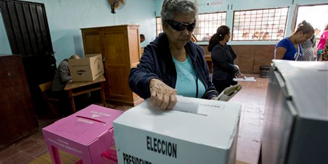 A woman casts her ballot during Honduras' general elections in Tegucigalpa, Honduras, Sunday, Nov. 24, 2013. Hondurans were choosing a new president Sunday in a country reeling from violence, poverty and the legacy of a 2009 coup, and if polls are accurate, the vote could fail to produce a clear winner. The election pits Xiomara Castro, whose husband Manuel Zelaya was overthrown in a military-backed coup, against Juan Orlando Hernandez, the candidate of the ruling conservative National Party.(AP Photo/Moises Castillo)