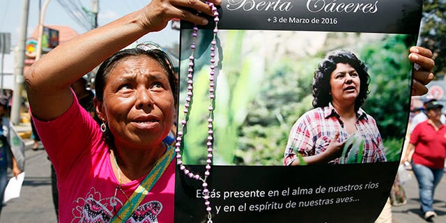 FILE - In this March 16, 2016, file photo, a woman holds up a poster with a photo of slain environmental leader Berta Caceres, during a protest march in Tegucigalpa, Honduras. Authorities said that unidentified gunmen killed Nelson Garcia, a colleague of Caceres, who was slain almost two weeks ago in similar circumstances. Honduran authorities announced Thursday, Sept. 8, that they have arrested a sixth suspect in the March killing of environmental activist Berta Caceres. (AP Photo/Fernando Antonio, File)