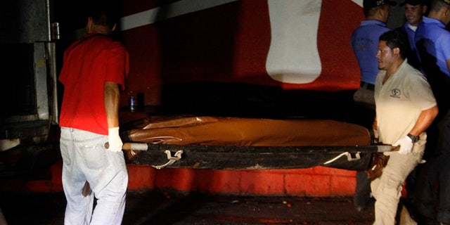 Forensic workers carry a body, on the outskirts of Tegucigalpa, Honduras, Sunday, Jan. 14, 2016. Authorities in Honduras say killers wielding assault rifles shot to death eight men when gathered in front of the local business. (AP Photo/Fernando Antonio)