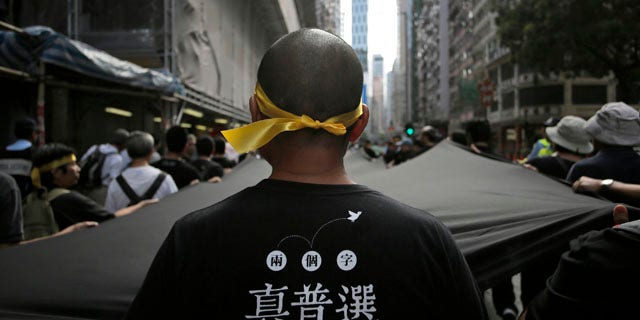 September 14, 2014: A protester stretches out a 500 meter long black cloth during a rally in a downtown street in Hong Kong.  The Chinese words on the T-shirt read 'Real Universal Suffrage'. (AP Photo/Vincent Yu)
