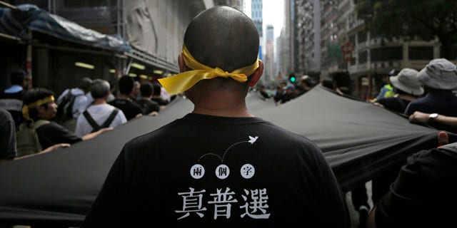 September 14, 2014: A protester stretches out a 500 meter long black cloth during a rally in a downtown street in Hong Kong. The Chinese words on the T-shirt read 'Real Universal Suffrage'. (AP Photo/Vincent Yu)