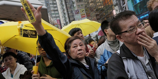 December 15, 2014: A protester raises a yellow banner that reads 'I want genuine universal suffrage' while police clear barricades and tents on a main road in the occupied areas at Causeway Bay district in Hong Kong. (AP Photo/Vincent Yu)