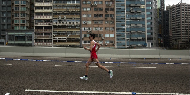 A participant runs past a old residential zone on the Connaught Road West Flyover as he competes in the Hong Kong marathon.