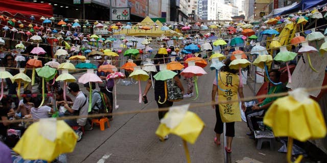 Protesters and people walk under hundreds of folded paper umbrellas at the occupied area in Causeway Bay, a shopping district of Hong Kong Thursday Oct. 30, 2014. Student democracy activists who have occupied Hong Kong streets for a month suggested Tuesday that direct negotiations with senior Chinese Communist Party officials could be a way to end their standoff with the local government. (AP Photo/Koji Ueda)