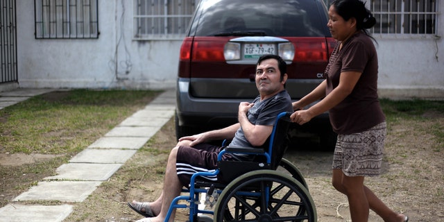 In this Thursday March 7, 2013 photo, Jacinto Rodriguez Cruz, 49, leaves his home on a wheelchair with the help of his wife, Belen Hernandez in the city of Veracruz, Mexico.  Cruz and another friend suffered serious injuries during a car accident last May 2008 in northwestern Iowa. After their employers insurance coverage ran out, Cruz, who was not a legal citizen, was placed on a private airplane and flown to Mexico still comatose and unable to discuss his care or voice his protest. Hospitals confronted with absorbing the cost of caring for uninsured seriously injured immigrants are quietly deporting them, often unconscious and unable to protest, back to their home countries. (AP Photo/Felix Marquez)