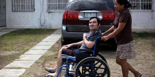 In this Thursday March 7, 2013 photo, Jacinto Rodriguez Cruz, 49, leaves his home on a wheelchair with the help of his wife, Belen Hernandez in the city of Veracruz, Mexico. Cruz and another friend suffered serious injuries during a car accident last May 2008 in northwestern Iowa. After their employers insurance coverage ran out, Cruz, who was not a legal citizen, was placed on a private airplane and flown to Mexico still comatose and unable to discuss his care or voice his protest. Hospitals confronted with absorbing the cost of caring for uninsured seriously injured immigrants are quietly deporting them, often unconscious and unable to protest, back to their home countries. (AP Photo/Felix Marquez)