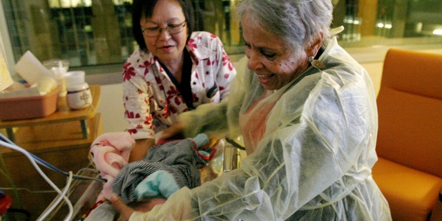 Hospital volunteer Gertie Rogers, 84, places a newborn baby back into a bed in the neonatal intensive care unit at the University of Chicago's Comer Children's Hospital in Chicago. (AP Photo/Martha Irvine)