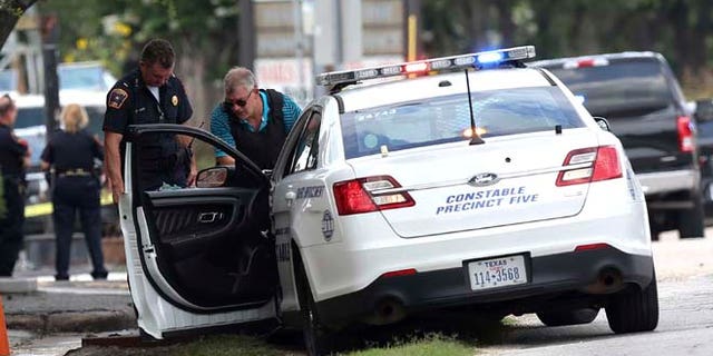 A C=constable car with a shot-out window remains at the scene where Houston police were investigating a shooting, Sunday, May 29, 2016, in Houston. A man came into an auto detail shop and began shooting, killing a man known to be a customer and putting a neighborhood on lockdown before being killed by a SWAT officer, police said. Several people were shot and injured. (Elizabeth Conley/Houston Chronicle via AP)