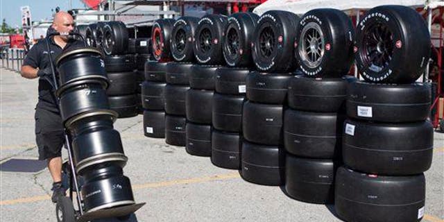 A technician carries rims to the Firestone Tires team as crews prepare for the Honda Indy Toronto IndyCar auto race in Toronto, Thursday, July 11, 2013.