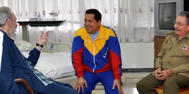 In this June 17, 2011, file photo released by Granma newspaper, Cuba's former President Fidel Castro, left, and his brother, President Raul Castro, right, speak with Venezuela's Hugo Chavez at a Cuban hospital as Chavez recuperates from surgery for a pelvic abscess.
