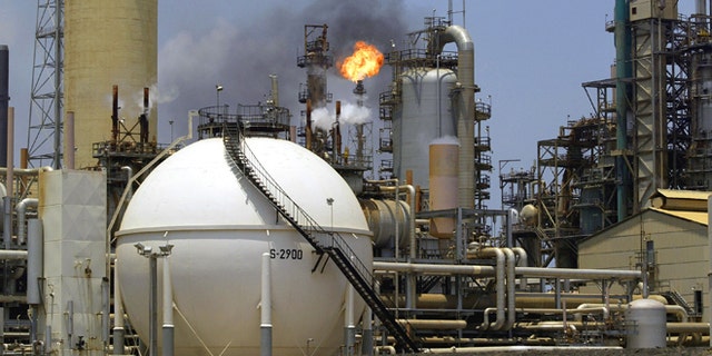 PARAGUANA, VENEZUELA - APRIL 4: A controlled flame burns behind a storage tank in the oil refinery complex of Amuay-Cardon April 4, 2003 in Paraguana, located about 350 miles West of Caracas, Venezuela. Amuay-Cardon, one of the world's largest oil refineries, will export approximately 87,000 barrels of gasoline per day in April, after gasoline exports resumed at the end of a two-month strike by oil workers. (Photo by Kimberly White/Getty Images)