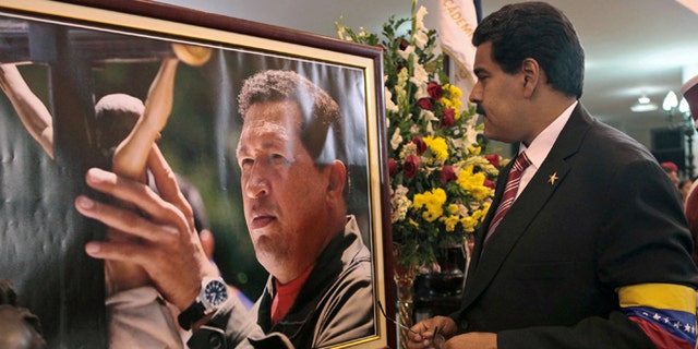 FILE -March 8, 2013 file photo released by Miraflores Press Office: Venezuela's President Nicolas Maduro stands in front of a portrait of Venezuela's late President Hugo Chavez. (AP Photo/Miraflores Press Office, File)
