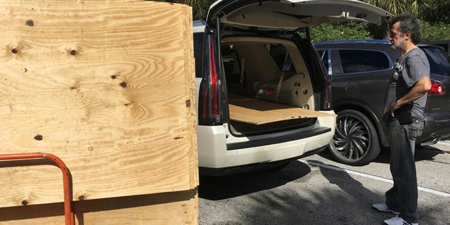 Danny Delarocca, of Boca Raton, loads plywood onto his brother's car at the Home Depot in Deerfield Beach, Fla. Tuesday, Oct. 4, 2016.