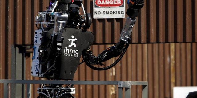 The Team IHMC Robotics Atlas "Running Man" robot built by Boston Dynamics raises its arms to celebrate after climbing the stairs during the finals of the Defense Advanced Research Projects Agency (DARPA) Robotic Challenge in Pomona, California June 6, 2015.