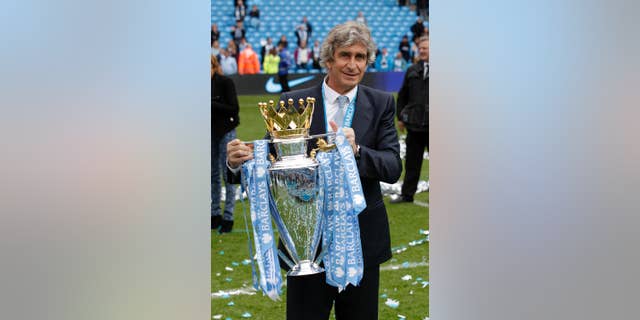El chileno Manuel Pellegrini, técnico del Manchester City, posa para los fotógrafos con el trofeo de la liga Premier inglesa tras el último partido de la temporada contra el West Ham en el estadio Etihad, en Manchester, Inglaterra, el domingo 11 de mayo de 2014. El City se coronó el domingo campeón con una cómoda victoria 2-0 sobre el West Ham. (AP Foto/Jon Super)