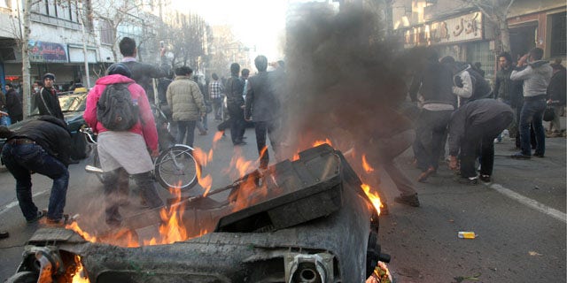 Feb. 14, 2011: This photo shows Iranian protestors attending an anti-government protest as a garbage can is set on fire, in Tehran, Iran.