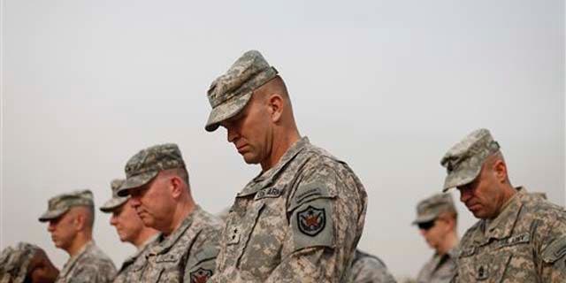 Military personnel lower their heads during ceremonies of the encasing of the US Forces Iraq colors, in Baghdad, Iraq, Thursday, Dec., 15, 2011. The ceremonies mark the official end of the US military mission in Iraq. (AP Photo/Pablo Martinez Monsivais, Pool)