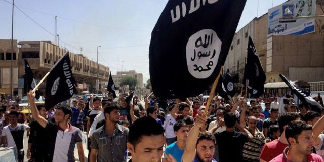 June 16, 2014: Demonstrators chant pro-Islamic State group slogans as they wave the group's flags in front of the provincial government headquarters in Mosul.