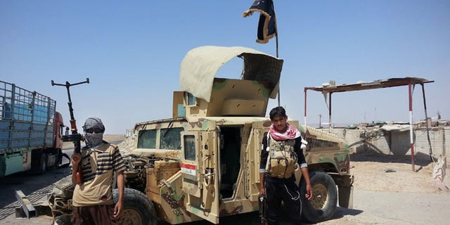 In this file photo taken Thursday, June 19, 2014, ISIS militants stand with captured Iraqi Army Humvee.