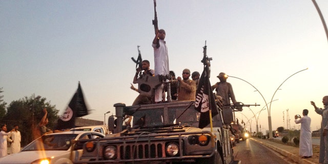 In this file photo taken Monday, June 23, 2014, fighters from the Islamic State group parade in a commandeered Iraqi security forces armored vehicle down a main road at the northern city of Mosul, Iraq.