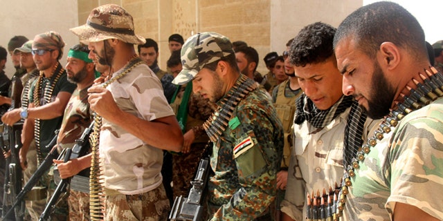FILE: May 21, 2015: Iraqi Shiite militiamen check their weapons against ISIS, in the predominately Sunni city of Nukhayb, in southwest Iraq.