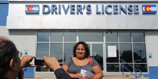 FILE - In this Aug. 1, 2014 file photo, immigrant and longtime resident in the United States Rosalva Mireles is photographed by Jesus Sanchez of Spanish language newspaper El Commercio, after Mireles was processed for her permanent driver's license, and received a temporary one to use until it is ready, at a Department of Motor Vehicles office, in Denver. Colorado Democrats are decrying a Republican decision to not add funding to a program allowing immigrants to get driver's licenses regardless of their legal status. There's been high demand for the program since it launched last year. (AP Photo/Brennan Linsley, file)
