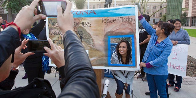 FILE - In this Dec 17, 2014, file photo, Erika Andiola gets her photo taken at the Arizona State Capitol in Phoenix, as thousands of young immigrants moved a step closer to getting driver's licenses in Arizona. A single mother battling cancer and a victim of domestic abuse are among the immigrants who qualify for Arizona driver's licenses but have been illegally denied the chance to drive a car, a group of advocacy organizations said in a new federal lawsuit. Denying licenses to some immigrants in the country illegally who have been granted deferred action, or protection from deportation, is unconstitutional, according to the claim filed Monday, Sept. 12, 2016 by the Mexican American Legal Defense and Educational Fund, the National Immigration Law Center and the Ortega Law Firm.(Nick Oza /The Arizona Republic via AP, File)