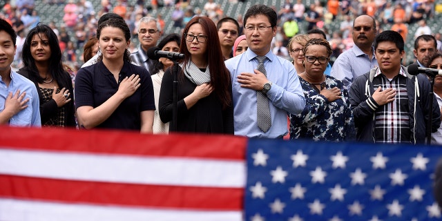 Thirty-two Southeast Michigan immigrants recite the "Pledge of Allegiance" as they are sworn in to become United States citizens during a naturalization ceremony prior to a baseball game between the Detroit Tigers and the Kansas City Royals, Thursday, June 29, 2017, in Detroit. This is the 10th year the ceremony has taken place at Comerica Park during the baseball season.