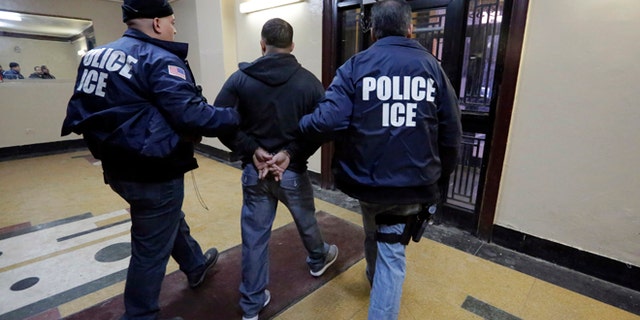 In this March 3, 2015 photo, Immigration and Customs Enforcement officers escort an arrestee in an apartment building, in the Bronx borough of New York, during a series of early-morning raids. Immigrant and Customs Enforcement say an increasing number of cities and counties across the United States are limiting cooperation with the agency and putting its officers in dangerous situations as they track down foreign-born criminals. Instead, more of its force is out on the streets, eating up resources and conducting investigations because cities like New York and states like California have passed legislation that limits many of the detention requests issued by immigration authorities. (AP Photo/Richard Drew)