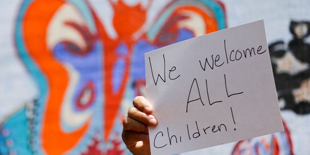 Ron Kohl holds up a sign during a rally in support of immigrants Wednesday, July 2, 2014, in San Diego. A group of about 70 people rallied in support of migrant children and families Wednesday, a day after U.S. Homeland Security buses carrying the migrants were routed away from American flag-waving protesters in Murrieta, Calif., and transported to a facility in San Diego. (AP Photo/Gregory Bull)