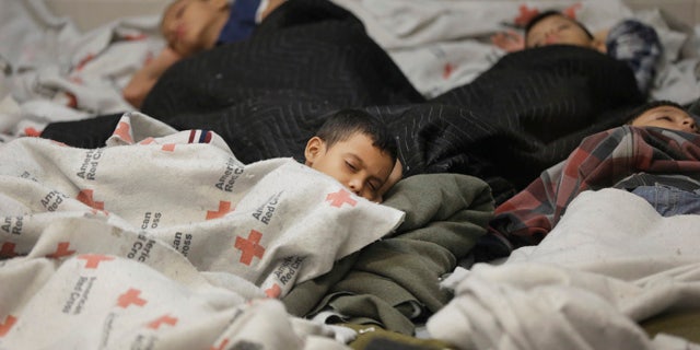June 18, 2014: Detainees sleep in a holding cell at a U.S. Customs and Border Protection processing facility in Brownsville,Texas. (AP Photo/Eric Gay, Pool)