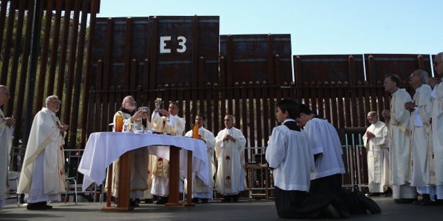 NOGALES, AZ - APRIL 01: Archbishop of Boston Cardinal Sean O'Malley (L), and fellow Catholic clergy stand next to the U.S.-Mexico border fence during a special 'Mass on the Border' on April 1, 2014 in Nogales, Arizona. Catholic bishops led by Cardinal O'Malley held the mass at the border fence to pray for comprehensive immigration reform and for those who have died along the border. (Photo by John Moore/Getty Images)