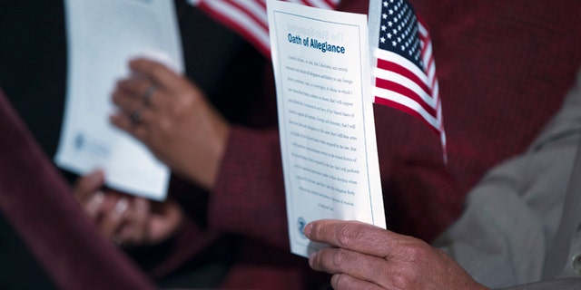 In this Dec. 15, 2015, photo, participants hold the "Oath of Allegiance" and American flags during a naturalization ceremony attended by President Barack Obama at the National Archives in Washington. More Americans favor than oppose a pathway to citizenship for immigrants who are living in the United States illegally, a new Associated Press-GfK poll shows. While most Republicans oppose such a path to citizenship, it doesn't seem to be a dealbreaker issue for them. (AP Photo/Evan Vucci)