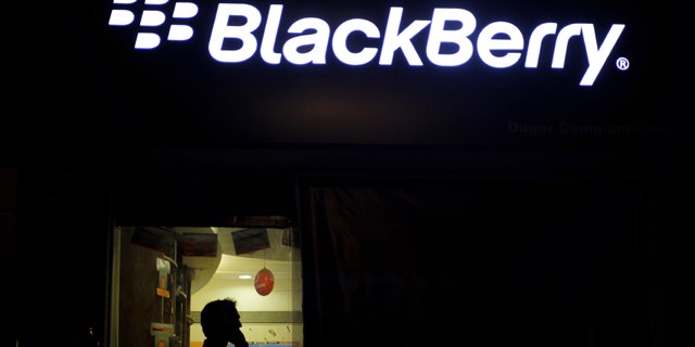 A man chats on his mobile as he walks past a BlackBerry mobile banner in Ahmadabad, India -- one of many countries debating what sort of access governments should have to data on the devices.