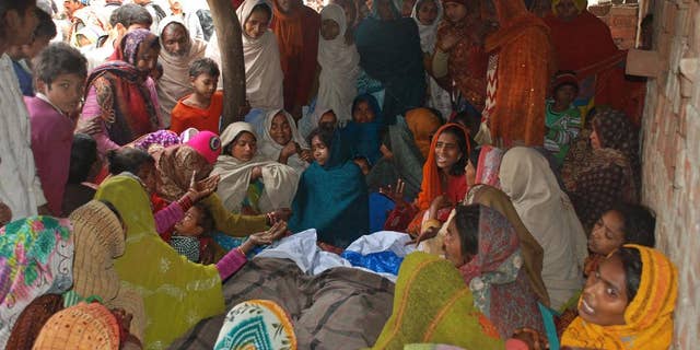 Indian women mourn around the bodies of two men, who died after consuming a bad batch of bootleg liquor in Datli village, about 30 kilometers (almost 20 miles) southwest of Lucknow, India, Tuesday, Jan. 13, 2015. More than 25 people were killed and at least 160 others hospitalized, officials said Tuesday. Many of the victims were among more than 200 people who had gathered to watch a cricket match Sunday evening in the village. (AP Photo/Sanjay Sonkar)