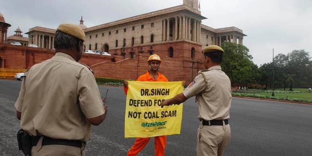 FILE- In this Aug. 21, 2012 file photo, Indian policemen prepare to remove a Greenpeace activist as he holds a banner near the area of government offices and the Indian Parliament in New Delhi, India. India's home ministry says it is temporarily suspending the registration of Greenpeace India because it is under-reporting foreign contributions and using them without government approval. (AP Photo, file)