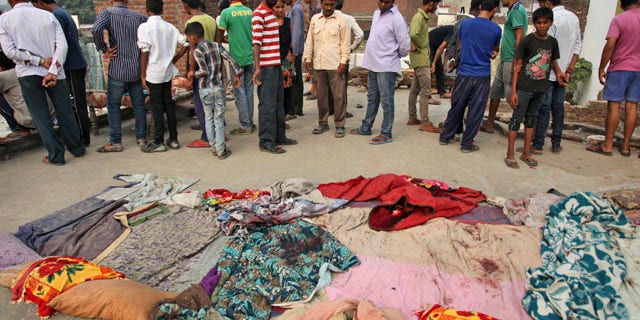 October 6, 2014: Indian villagers gather near bed sheets stained with blood in alleged firing from the Pakistans side while the residents were asleep on roof of their house, at Masha da kothe village, in Arnia Sector near the India-Pakistan international border, about 30 miles from Jammu. (AP Photo/Channi Anand)