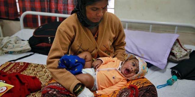 Landslide survivor Pramila Lende holds her son Rudra who was injured in the same landslide, at a hospital in Manchar, in the western Indian state of Maharashtra, India, Friday, Aug. 1, 2014. One of the few people pulled alive from the rubble in the hours after the landslide were Lende and her 3-month-old son. Lende said she was feeding her son when she heard the roar of earth and mud ripping down the hillside. Rescuers searching for dozens of people still missing after the landslide. Chances of finding anyone alive were increasingly slim. (AP Photo/Rafiq Maqbool)