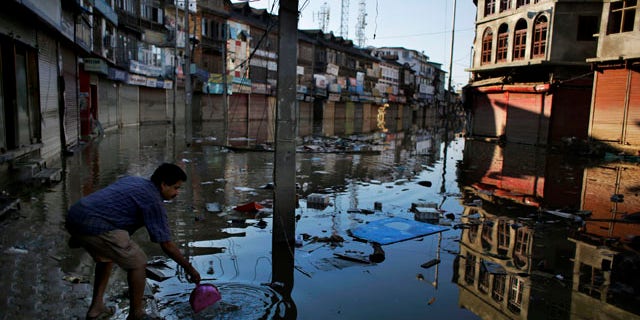 September 16, 2014: A shopkeeper throws the silt he removed from his shop into the receding flood waters in Srinagar, Indian-controlled Kashmir. (AP Photo/Altaf Qadri)
