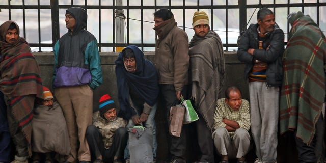 Impoverished and homeless people stand in a queue to receive free food from a volunteer organization in front of a temple, in New Delhi, India, Tuesday, Jan. 1, 2013. India will send billions of dollars in social welfare money directly to its poor under a new program inaugurated Tuesday, aiming to cut out the middlemen blamed for the massive fraud that plagues the system. (AP Photo/Manish Swarup)