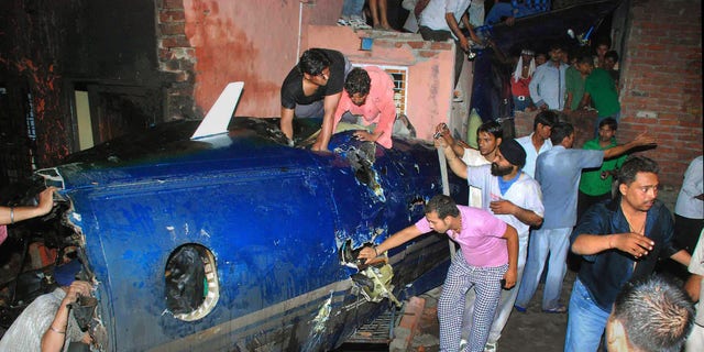 May 25: Indian residents search around the wreckage of a small plane after it crashed into a residential community in Faridabad, near New Delhi, India. A government official says the crash of a small chartered plane in a residential area on the outskirts of the Indian capital has killed at least 10 people and injured another two. (AP)