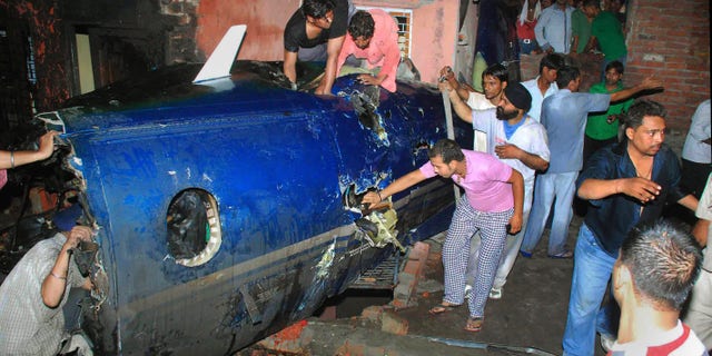 May 25: Indian residents search around the wreckage of a small plane after it crashed into a residential community in Faridabad, near New Delhi, India. A government official says the crash of a small chartered plane in a residential area on the outskirts of the Indian capital has killed at least 10 people and injured another two. (AP)