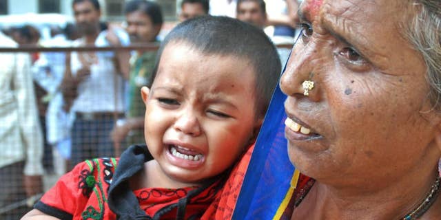 A woman holds a crying child as relatives of victims gather at the spot of a stampede at the Kamta Nath Hindu temple in Chitrakoot, India, Monday, Aug. 25, 2014. A pre-dawn stampede killed 10 people Monday as tens of thousands of Hindus were worshipping in an annual procession marking the holy day of Somvati Amavasya. (AP Photo/Amar Deep)