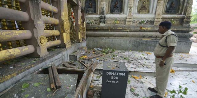 July 7, 2013: A security officer inspects the site of an explosion on the campus of the Mahabodhi Temple, the Buddhist Great Awakening temple, in Bodhgaya, about 130 kilometers (80 miles) south of Patna, the capital of the eastern Indian state of Bihar. A series of small blasts hit three Buddhist temples in eastern India early Sunday, injuring at least two people, police said.