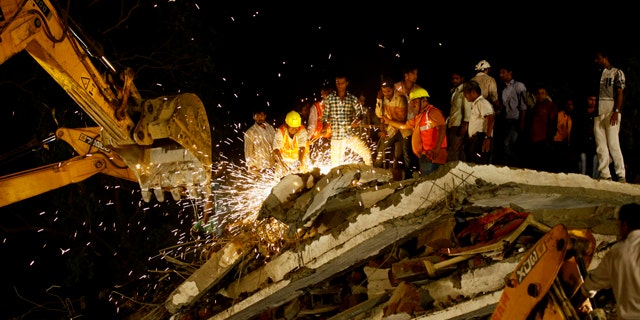 April 4, 2013: Rescue workers look for trapped people after a residential building collapsed in Thane, Mumbai, India.