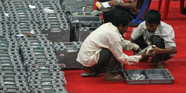 Indian workers hold an electronic voting machine during the counting of votes at a counting center in Gauhati, India, Friday, May 16, 2014. Opposition leader Narendra Modi won India's election by a landslide Friday, according to preliminary results that showed his party easily driving out the long-dominant Congress party in the most commanding election victory India has seen in more than a quarter century. The full results are expected later in the day but it's unlikely that Modi's party would see a significant reversal. (AP Photo/Anupam Nath)